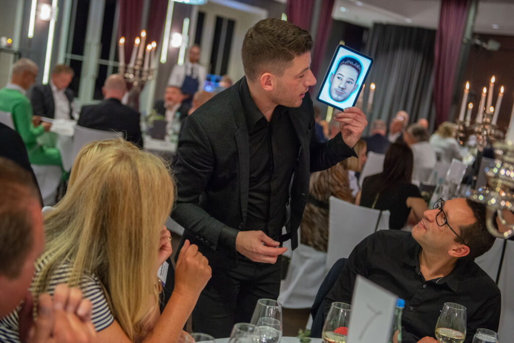 Close-Up-Zauberer mit iPad am Tisch der Gäste